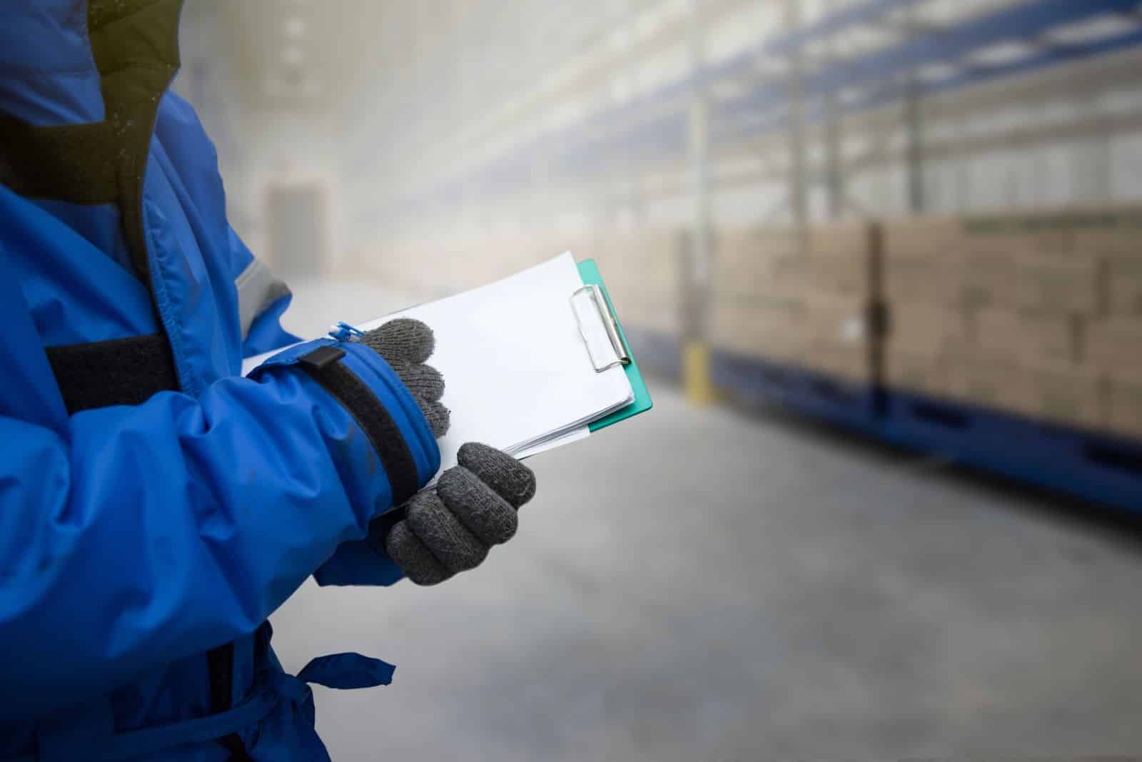 Person holding checklist in cold refrigeration space